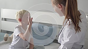 Cheerful greeting of a doctor and a boy sitting on the mend in a hospital