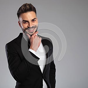 Cheerful groom holding his hand on his chin and laughing