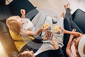 Cheerful group of friends eating popcorn at home