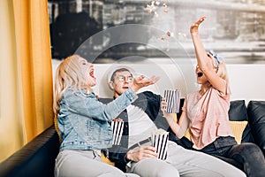 Cheerful group of friends eating popcorn at home