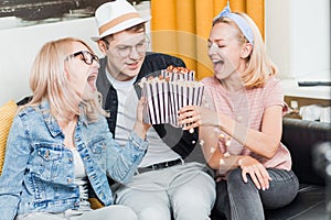 Cheerful group of friends eating popcorn at home