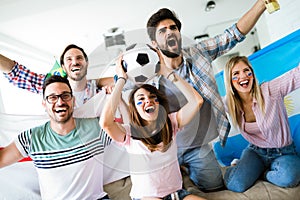 Cheerful group of friends watching football game on tv.