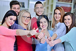 Cheerful group of students smiling at camera with thumbs up, success and learning concept