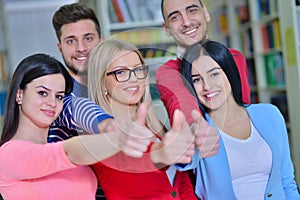 Cheerful group of students smiling at camera with thumbs up, success and learning concept