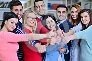 Cheerful group of students smiling at camera with thumbs up, success and learning concept