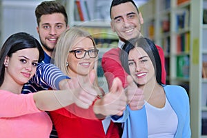 Cheerful group of students smiling at camera with thumbs up, success and learning concept