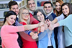 Cheerful group of students smiling at camera with thumbs up, success and learning concept