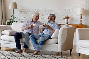 Cheerful grownup son and happy senior father enjoying coffee break