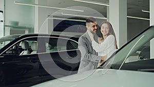 Cheerful guy is making surprise for his wife closing her eyes with his hands and leading her to beautiful new car is
