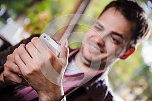 Cheerful guy at the restaurant outdoors using a mobile phone, hands close up