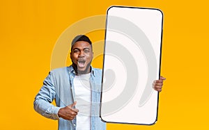 Cheerful guy showing big white empty smartphone screen and like