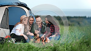 Cheerful guy showing photo on mobile to happy girls surrounded by nature. Wide shot on RED camera