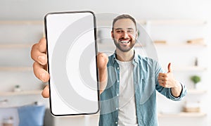 Cheerful guy showing white empty smartphone screen, closeup