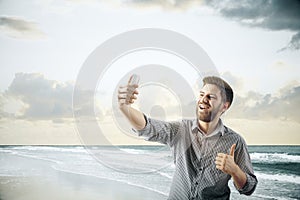 Cheerful guy taking selfie at the beach