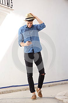 Cheerful guy walking and reading text message on cell phone