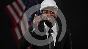 Cheerful handsome African American man in formal suit and hard hat presenting real estate development program showing