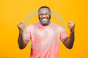 Cheerful handsome African guy making yes gesture while excited about winning. Ecstatic young fan rooting and expressing support.