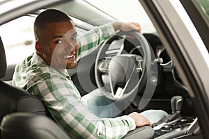 Handsome African man choosing new car at dealership