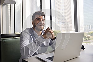 Cheerful handsome Arab online project executive man sitting at laptop