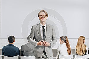 cheerful handsome coach looking at camera during business training