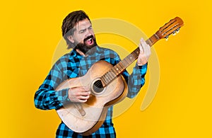 Cheerful handsome man guitarist playing guitar and singing country song, music