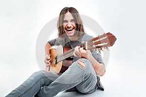 Cheerful handsome man with long hair sitting and playing guitar