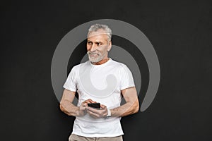 Cheerful handsome mature old man using mobile phone.