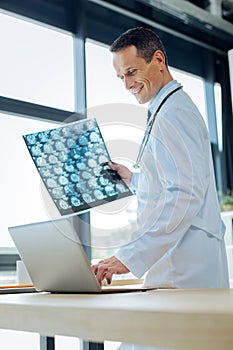 Cheerful handsome radiologist using a laptop