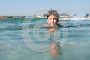 Cheerful handsome teen boy swiming in turquoise blue sea water above water surface and underwater. Beach, summer vacation, teenage