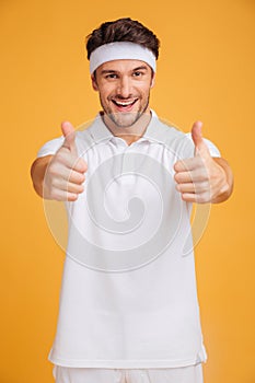 Cheerful handsome young sportsman showing thumbs up with both hands