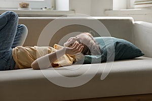 Cheerful happy adorable little kid girl resting on soft couch