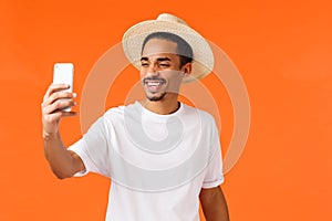 Cheerful happy african-american guy taking selfie on vacation under sun near sandy beautiful beach tropical island