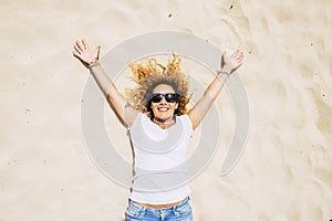 Cheerful happy caucasian adult young woman lay down on the sand at the beach smiling and laughing enjoying the outdoor leisure