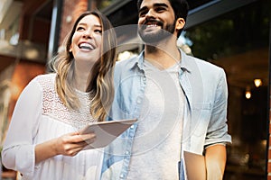 Cheerful happy couple using digital tablet outdoors