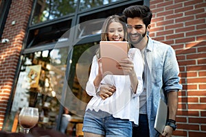 Cheerful happy couple using digital tablet outdoors