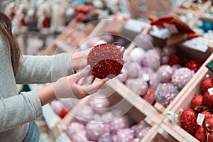 Cheerful happy customer girl choosing Christmas tree decoration balls