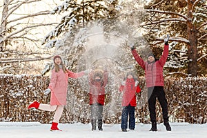 Cheerful happy family of four throws snow in winter. people in bright winter clothing