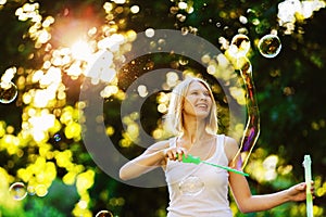 Cheerful happy girl with beautiful smile is blowing bubbles