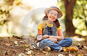 cheerful happy girl with magnifying glass studies the environment in summer in nature