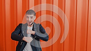 Cheerful happy guy in a black leather jacket moves dances and sings against the orange background