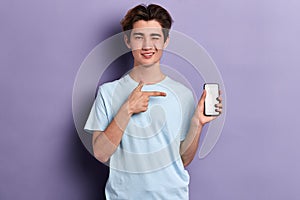 Cheerful happy handsome guy pointing at smart phone