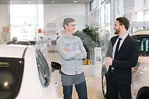 Cheerful happy man preparing to buy new car in auto dealership.