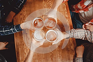 Cheerful and happy old friends are drinking draft beer at pub bar clink glasses. Top view. Friendship concept