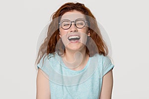 Cheerful happy red-haired young woman in glasses laughing out loud