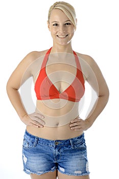 Pretty young blonde woman wearing red bikini top and jeans shorts in studio