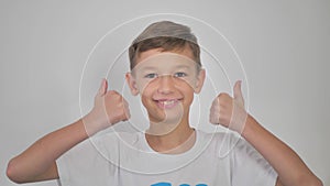 Cheerful happy teenager one on background shows agreement sign. The guy holds his thumb up. Sign of approval. Class. The