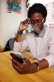 Cheerful and happy young black businessman messaging online, checking social media news feed, using free wireless