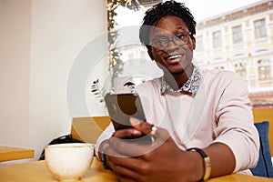 Cheerful and happy young black businessman messaging online, checking social media news feed, using free wireless