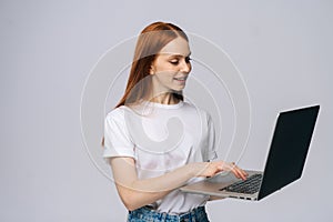 Cheerful happy young business woman or student holding laptop computer and looking away.