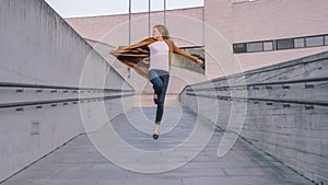 Cheerful and Happy Young Woman Actively Dancing and Jumping While Walking Down a Concrete Urban Pa